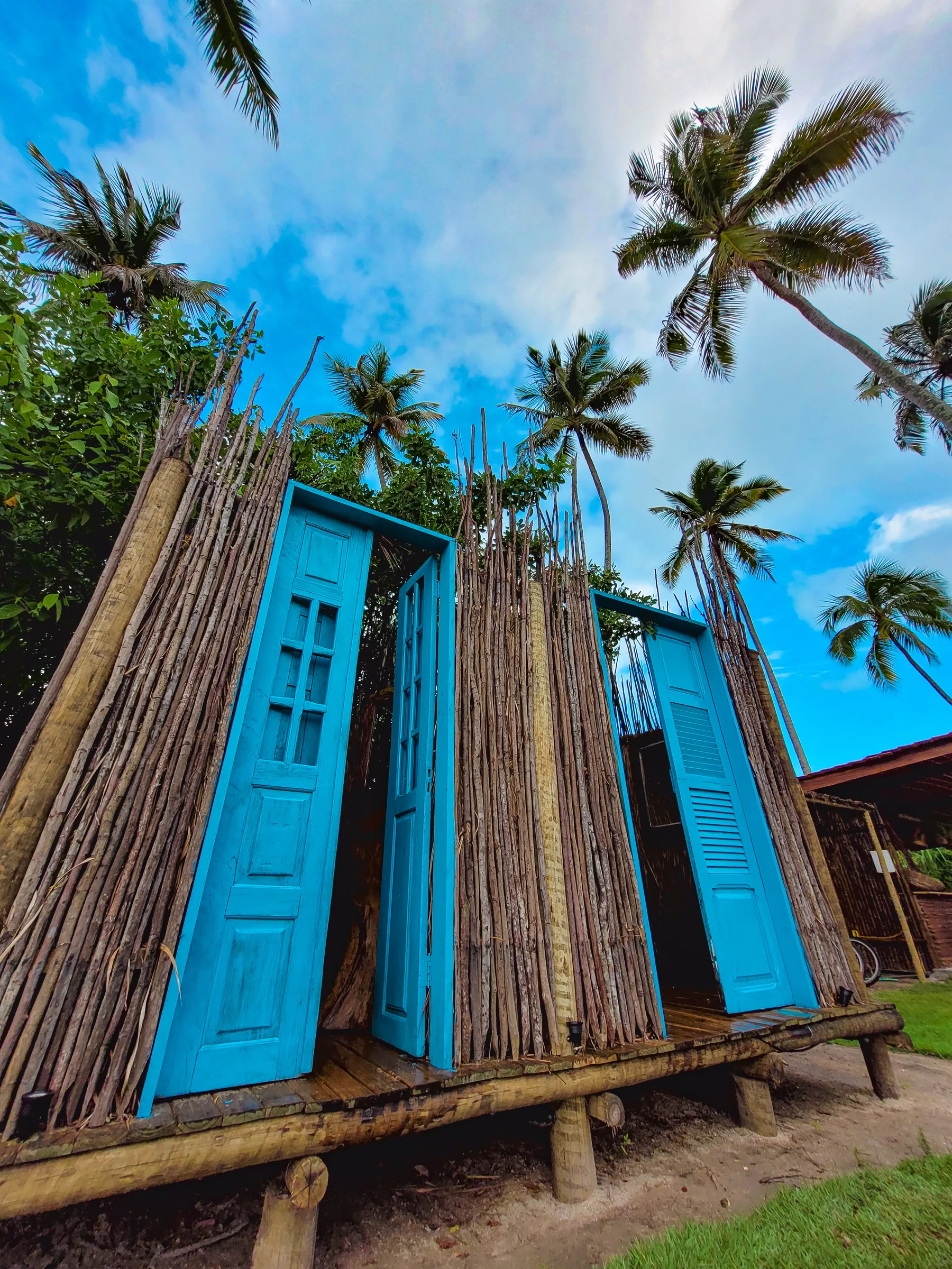 Entrada do Taboo Milagres, com portas azuis e elementos naturais